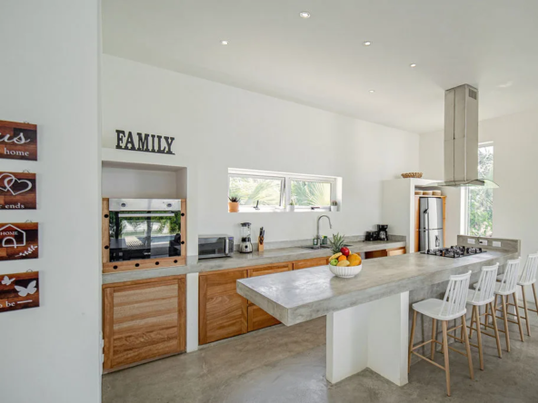 modern kitchen with concrete island, wood cabinets, and bar seating
