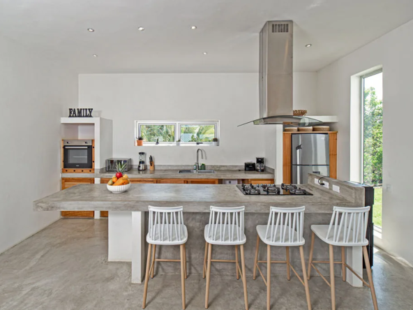 modern kitchen with concrete island, bar stools, and stainless hood