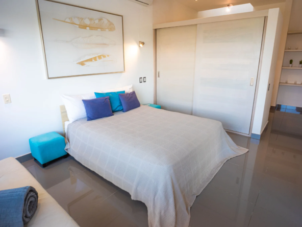 modern bedroom with white bedding, blue pillows, and sliding closet doors
