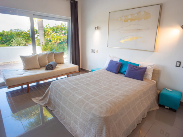 modern bedroom with queen bed, teal accents, garden view