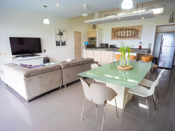 open-plan living dining kitchen area with glass table and sectional sofa